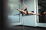 Pole dancer practicing pole dance in fitness studio