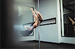 Pole dancer practicing pole dance in fitness studio