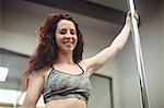 Portrait of pole dancer holding pole in fitness studio