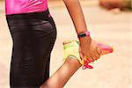 Young people doing sport activities, woman runner stretching leg using fit watch. Concept of leisure, health, recreation, fitness, lifestyle, exercising, training, workout
