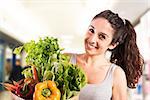 Smiling girl at supermarket with bag of vegetables