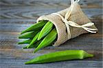 A heap of raw okra or Lady's fingers or gumbo in a bag on wooden background