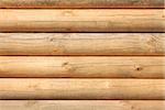 Horizontal parallel large new wooden logs in sunlight, close-up and detailed