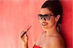 Young hispanic people smoking e-cig, pretty sensual latina woman with electronic cigarette, happy sexy girl with sunglasses smiling and blowing smoke. Portrait looking at camera