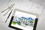 Computer Tablet Showing House Illustration Sitting On House Plans With Pencil and Compass.