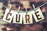 The word "CURE" stamped on cards and pinned to an old piece of twine over a rusted metal background.