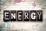 The word "ENERGY" written in vintage, dirty metal letterpress type on a whitewashed wooden background with ink and paint stains.