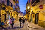 People Walking down Cobblestone Street at Dusk in Cefalu, Sicily, Italy