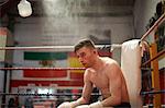 Boxer sitting in corner of boxing ring, exhausted