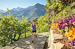 Young woman running along rural pathway, Meran, South Tyrol, Italy