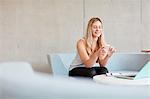 Young female student sitting on study space sofa reading smartphone texts at higher education college