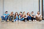 Group portrait of male and female students sitting on floor in a row at higher education college