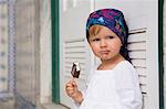 Portrait of female toddler leaning against shutters eating ice lolly, Beja, Portugal