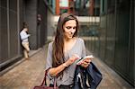 Young businesswoman texting on smartphone outside office, London, UK