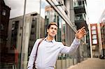 Young businessman hailing a cab outside office, London, UK