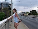Young female runner stretching legs on highway bridge at dawn