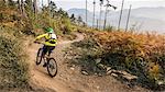 Mid adult woman cycling up dirt track, Finale Ligure, Savona, Italy