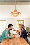 Couple face to face at dining table smiling