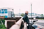 Mature male motorcyclist watching from roadside