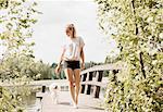 Woman with Coton de tulear dog strolling on lake pier, Orivesi, Finland