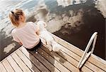 Woman sitting with Coton de tulear dog on lake pier, Orivesi, Finland