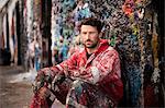 Portrait of male ship painter sitting against paint splattered wall
