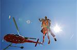 Tandem sky divers free falling with helicopter above, Interlaken, Berne, Switzerland