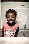 Young African boy sitting inside his rural home, smiling at camera