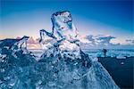 Jokulsarlon, Iceland. A transparent block of ice and a photographer on the Breidamerkursandur black beach.