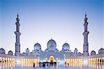 United Arab Emirates, Abu Dhabi. The courtyard and white marble exterior of Sheikh Zayed Grand Mosque.  The spectacular evening lighting varies from white to blue according to the phases of the moon.