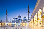 United Arab Emirates, Abu Dhabi. The courtyard and white marble exterior of Sheikh Zayed Grand Mosque. The spectacular evening lighting varies from white to blue according to the phases of the moon.