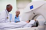 Doctors interacting with patient in scanning room at hospital