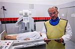 Doctor holding digital tablet and patient lying on x ray machine in hospital