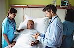 Male doctor showing report to senior patient on digital tablet in hospital