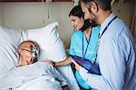 Nurse consoling senior patient with doctor in hospital