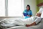 Nurse interacting over a report with senior patient in hospital