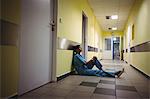 Depressed nurse sitting in hospital corridor