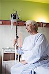 Thoughtful senior woman sitting on bed in hospital