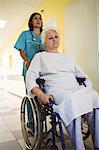 Nurse pushing a senior patient on a wheelchair in hospital