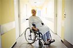 Thoughtful senior woman sitting on wheelchair in hospital corridor