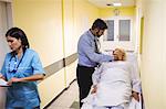 Doctor examining senior patient in hospital corridor