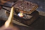 Goldsmith crafting ring by burner in workshop