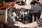 Male worker in bakery, using coffee machine, close-up