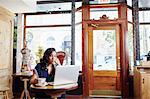 Young woman sitting in cafe, using laptop