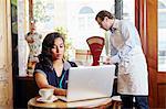 Young woman sitting in cafe, using laptop