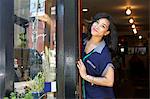 Female worker in bakery, standing in doorway, turning sign to open