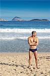 Mature man standing on beach, Ipanema, Cagarras islands, Rio de Janeiro, Brazil