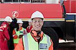 Happy engineer on oil rig, colleagues working in background