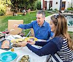Mature couple serving food at garden table