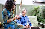 Mature couple chatting on patio at garden party